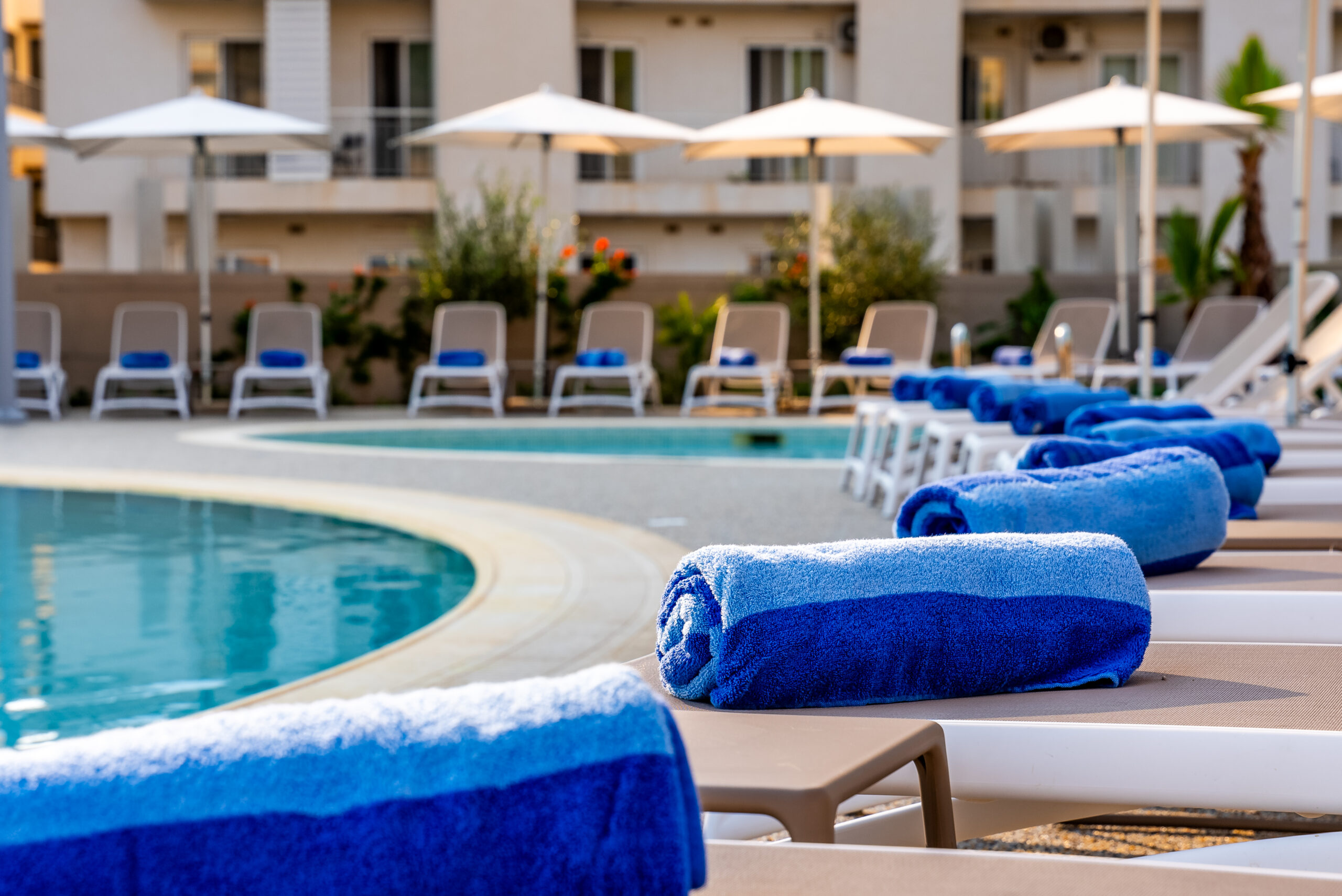 Deckchairs around a pool, with towels on them