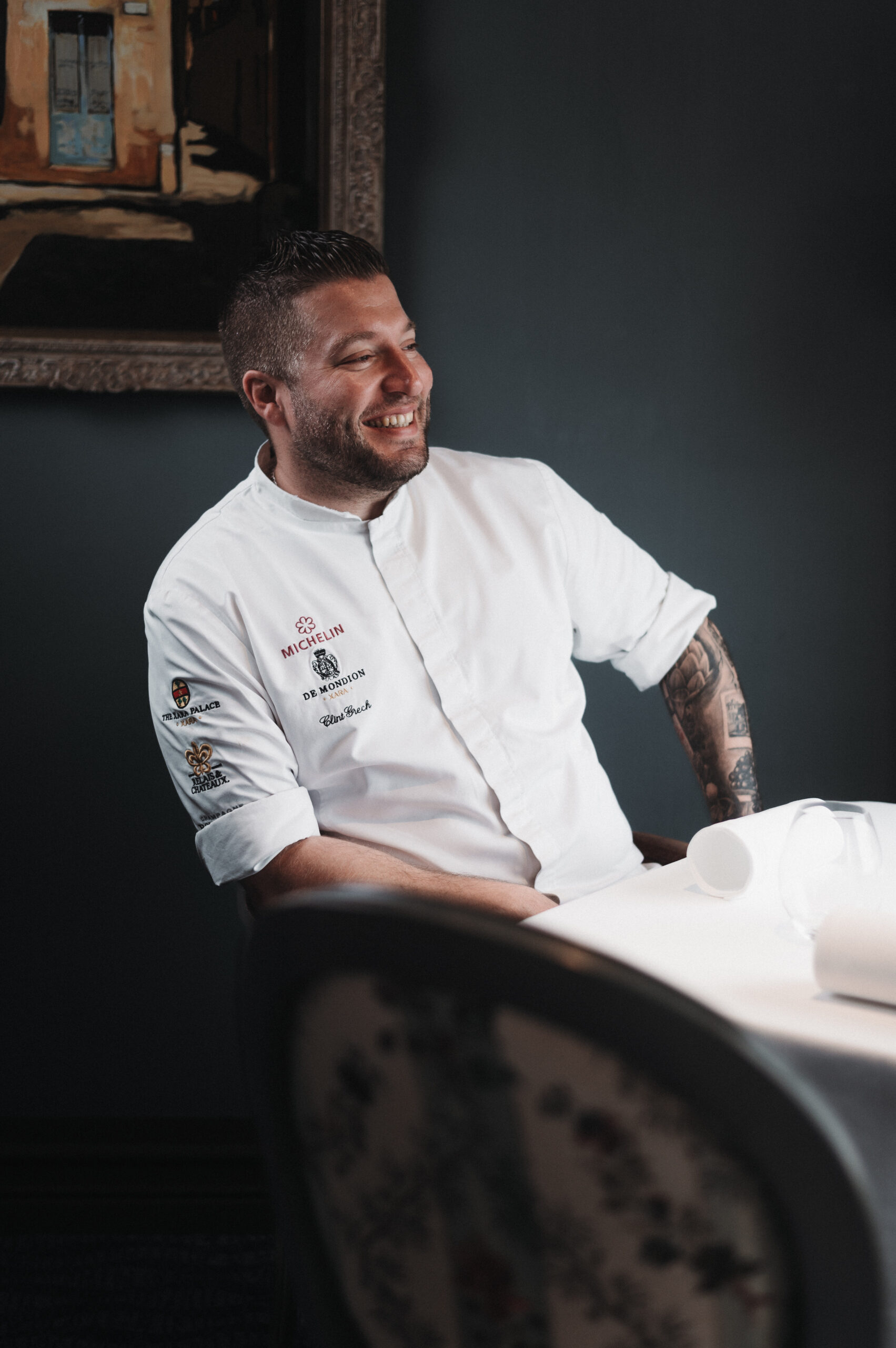 A chef, smiling and sitting at a restaurant table